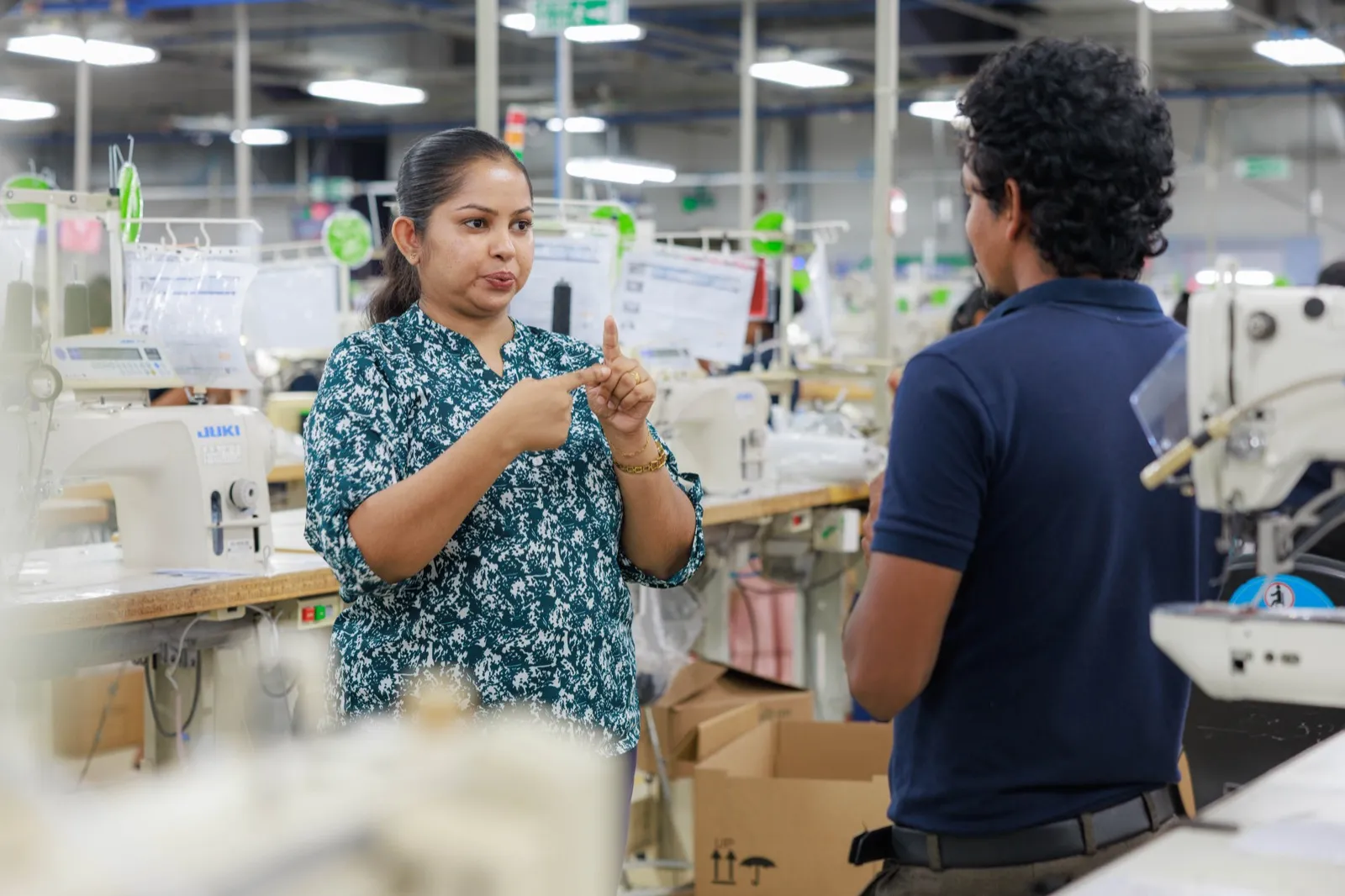 Two MAS team members communicating in sign language on the factory floor