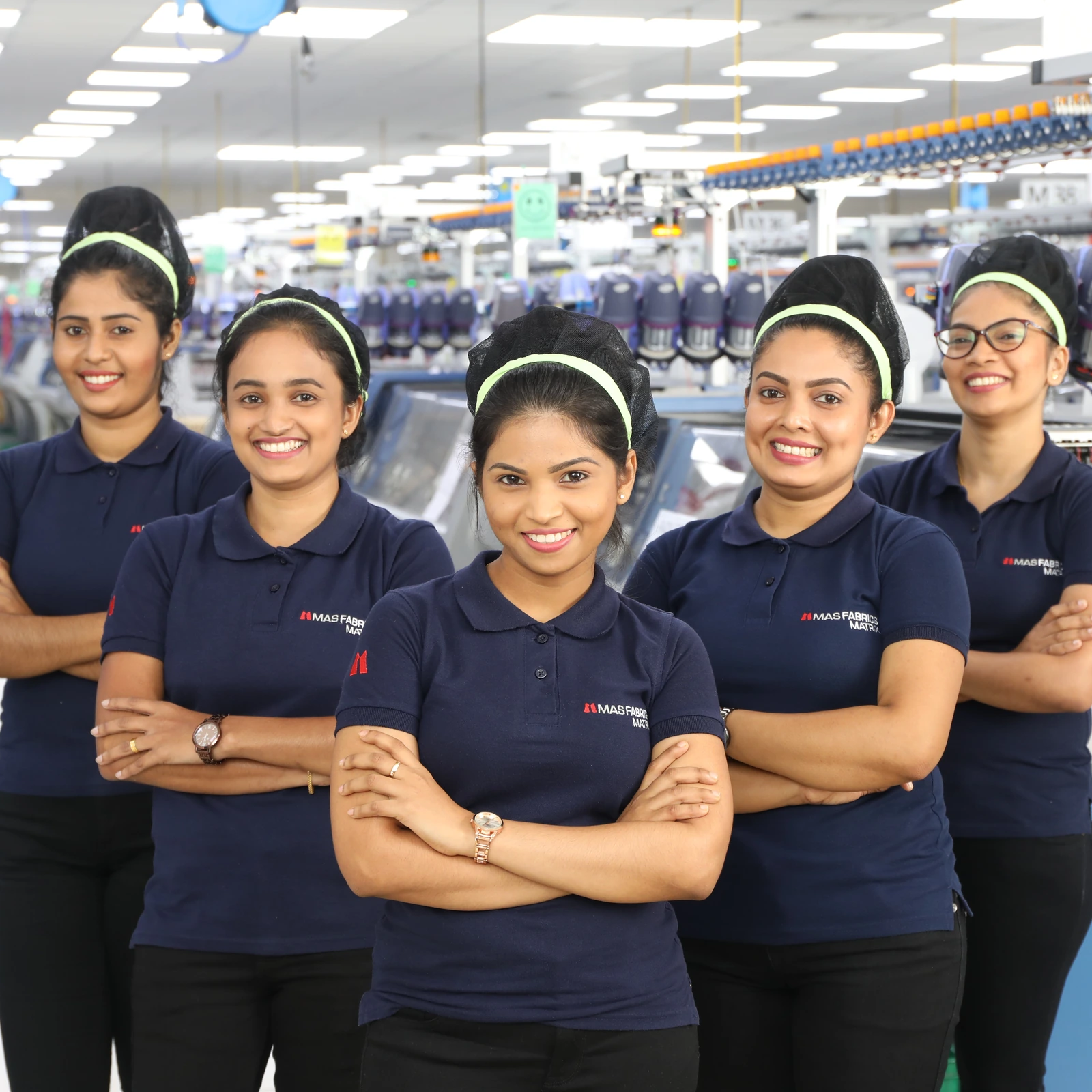 MAS team members in navy polos, arms crossed, on the production floor