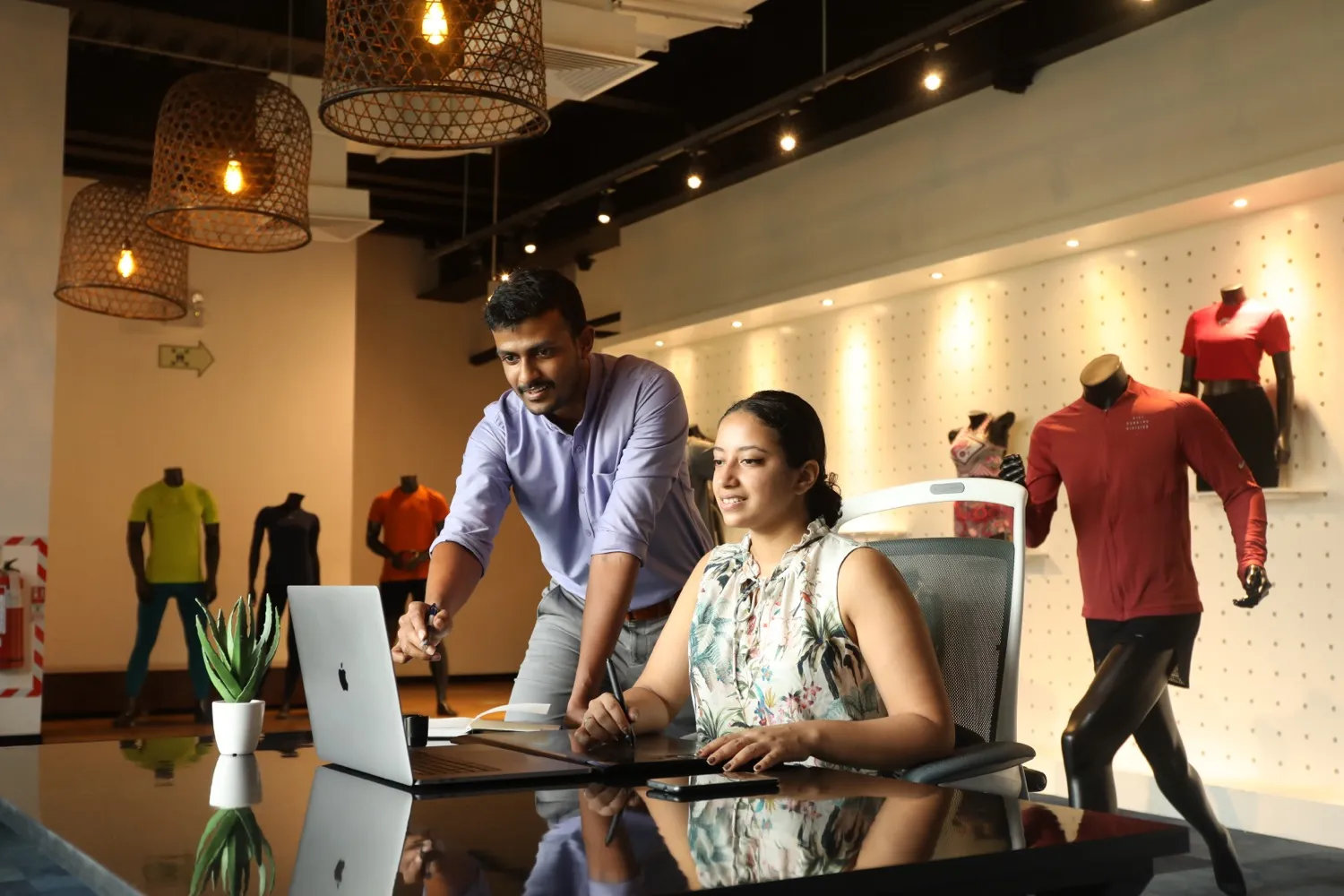 Two MAS colleagues collaborating over a laptop at a workstation